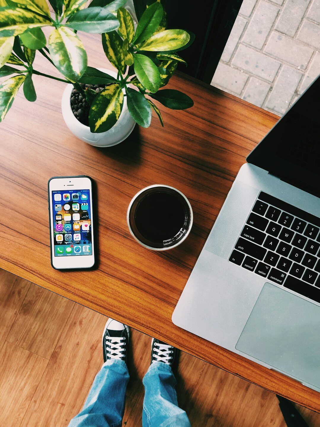 Overhead view of a desk with a laptop showing a website design and a coffee cup